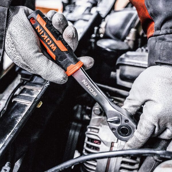 Close-up of hands wearing WOKIN gloves using WOKIN ratchet wrench to tighten a bolt on a car engine component