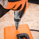 Close-up of gloved hand using a Wokin impact screwdriver from the 14pcs set to drive a screw
