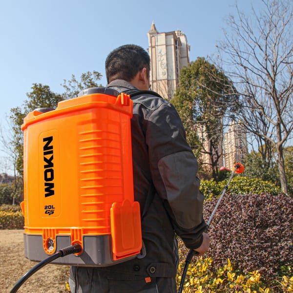 Person using WOKIN 20V Cordless Pressure Sprayer outdoors, demonstrating practical application in urban landscaping